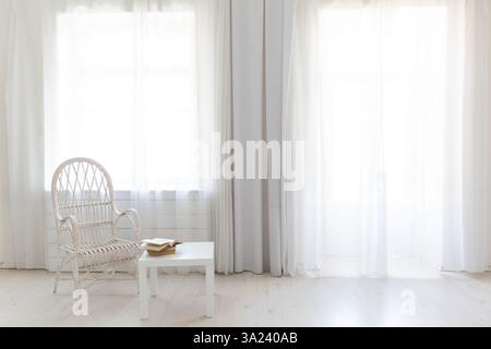 Chair and table with books in the interior of an empty room with a window Stock Photo