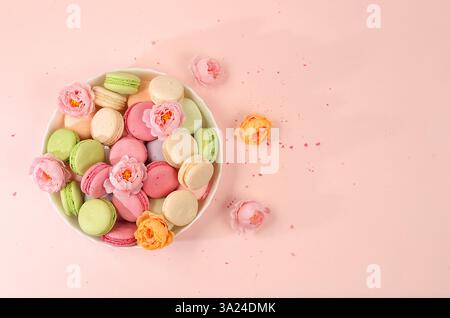 Fresh colorful macaroons in a gift box with flowers, top view. Modern bakery concept, business card for advertising or invitation. Delicious tradition Stock Photo