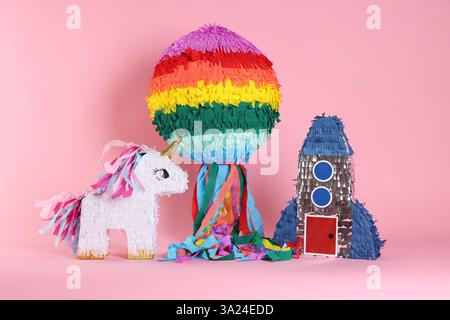Different bright colorful pinatas on pink background Stock Photo