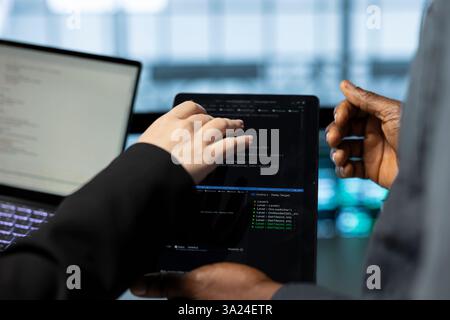 Engineers in data center using laptop and tablet, employing machine learning models. Close up of employees using devices to fulfill infrastructure needs, allocating resources efficiently Stock Photo