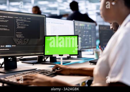 Computer scientist in data center updates rigs systems on green screen tablet to protect servers from exploitable software vulnerabilities. System administrator using mockup device to look for errors Stock Photo