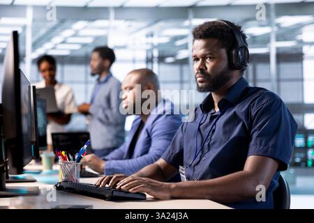 Data center worker hearing songs in headphones while using programming languages to construct algorithms and build applications. Server hub employee listening music, debugging and optimizing code Stock Photo