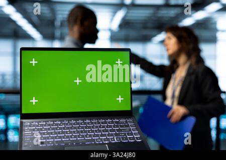 Mockup laptop used by data center admins in blurry background reviewing equipment diagnostics. Close up of chroma key notebook used by workers adjusting server room configurations Stock Photo