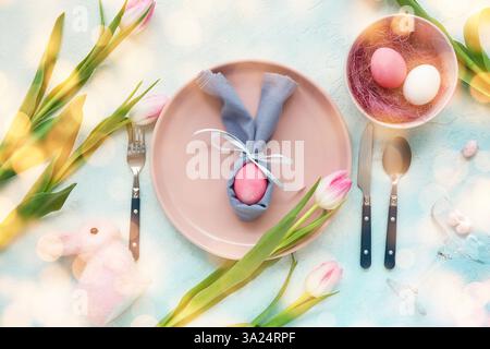 Stylish table setting for Easter celebration with tulips on light blue background Stock Photo