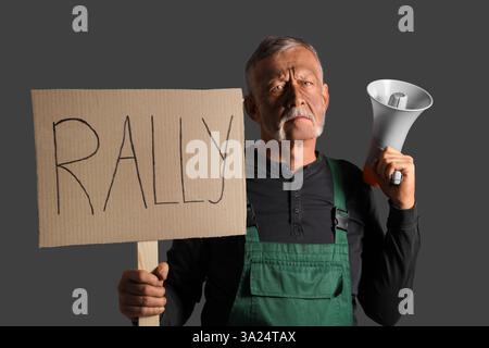 Protesting miner man with placard and megaphone on dark background Stock Photo