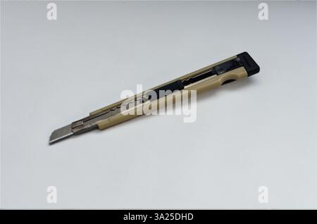 Gold and Black Utility Knife on a Neutral Background for Office Tasks Stock Photo