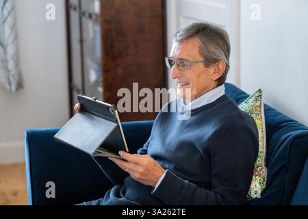 Man sitting on sofa using tablet. Stock Photo