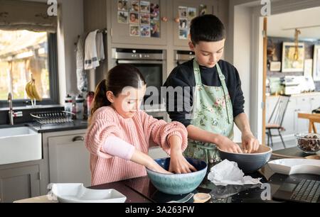 Boy and girl baking together in kitchen. Stock Photo