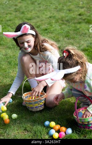 Two girls collecting Easter eggs in garden. Stock Photo