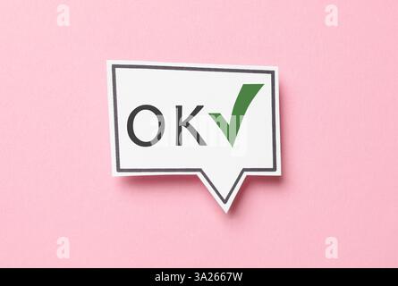 Speech bubble with abbreviation OK and check mark on pink background Stock Photo