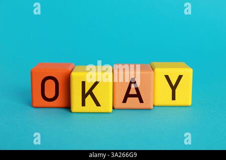 Colorful cubes with word Okay on light blue background Stock Photo