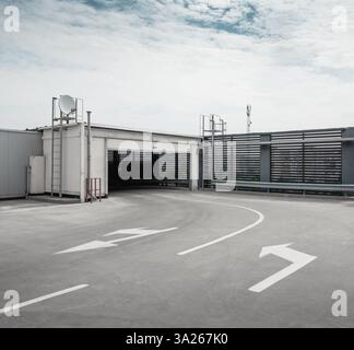 Exit from the upper floor of multi-storey parking garage. Empty turn with arrows on the floor directing the lanes. Stock Photo