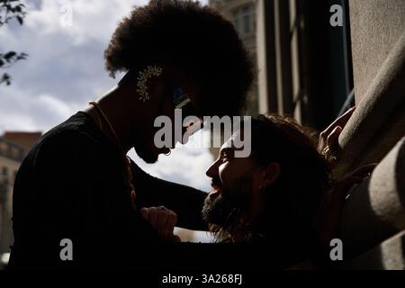 Two men are embracing and smiling, enjoying a romantic moment together in an urban setting Stock Photo