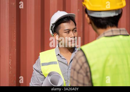 Project Coordination. Young engineers collaborating on logistics in a construction setting. Stock Photo