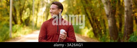 Handsome man with tattoos strolls down a tree lined path, showcasing a relaxed and modern style. Stock Photo