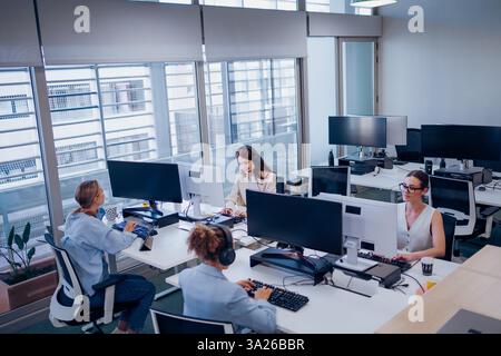 Modern Office Collaboration Features Professionals Actively Working at Their Desks Stock Photo