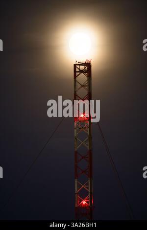 Lunar eclipse at dusk with transmission tower Stock Photo