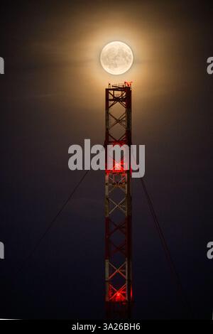 Lunar eclipse at dusk with transmission tower Stock Photo