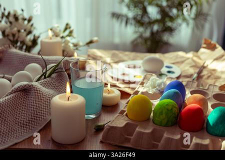 A table adorned with pastel-colored Easter eggs, candles, and natural decor sets the ambiance for a spring celebration. The activity involves decorati Stock Photo