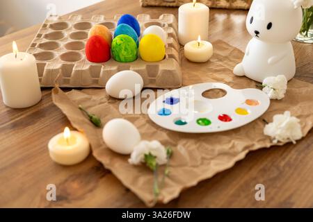A lively display of decorated Easter eggs arranged around a white bunny figurine. The palette, filled with vibrant paints, is ready for creativity, wh Stock Photo