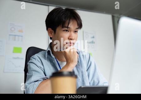 Focused Work and Productivity. A young professional engaged in deep thought while analyzing data on a laptop. Stock Photo