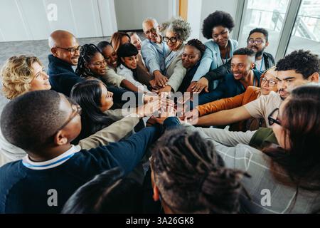 Multiethnic business colleagues displaying teamwork and unity by joining hands together. Emphasizing diversity, collaboration, and community in a mode Stock Photo