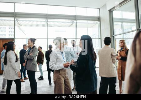 Diverse group of professionals networking, engaging in conversations, and building business relationships at a corporate event. Stock Photo