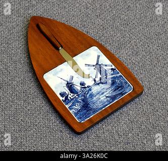 Wooden cheeseboard with knife and blue and white tile. Netherlands. Stock Photo