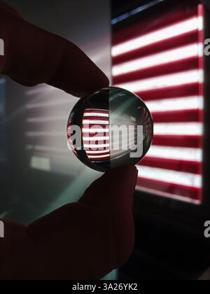 crystal ball reflecting red and white striped window blinds, creating an optical illusion with light and shadows Stock Photo
