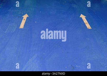 Two white arrows  and some tire tracks on the blue floor of a car workshop, in the town of Moniquira, in the eastern Andean mountains of Colombia. Stock Photo