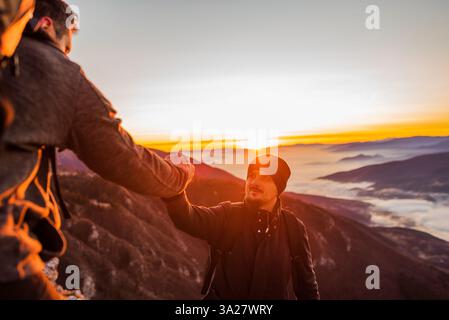 Hiking team people helping each other friend giving a helping hand while climbing up on the mountain adventure travel concept of support trust Stock Photo