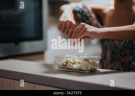 Woman squeezing lemon over fresh salad in a modern kitchen Stock Photo