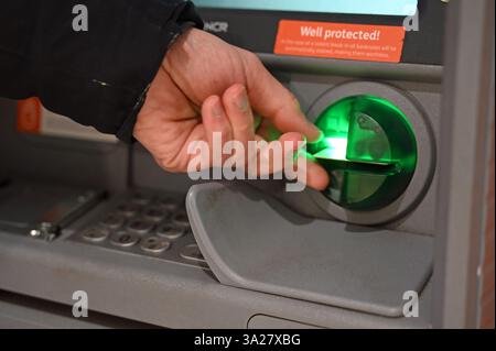 Leipzig, Germany. 12th Mar, 2025. A man pulls his bank card out of the dispenser of an ATM. Credit: Elisa Schu/dpa/Ģ����ý Live News Stock Photo