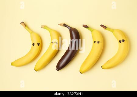 Stop racism. One dark banana among yellow ones on beige background, flat lay Stock Photo