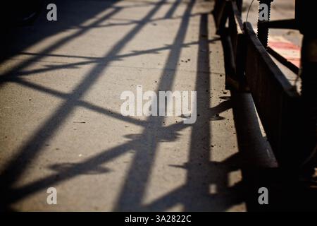 A close-up view of shadows cast on a concrete surface, showcasing intricate patterns created by a nearby structure. The lighting highlights the textur Stock Photo