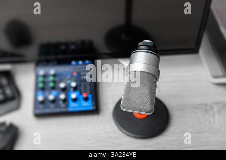 A professional condenser microphone on a desktop stand is set up in a modern gaming and recording workstation Stock Photo