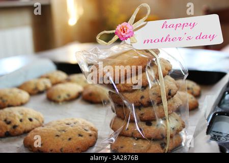 mother's Day cookie gift box, with greeting card and rose placed on baking tray where there are many other cookies Stock Photo