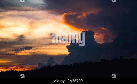 A mountain silhouette set against an orange sky and clouds during sunset at treasure mountain Stock Photo