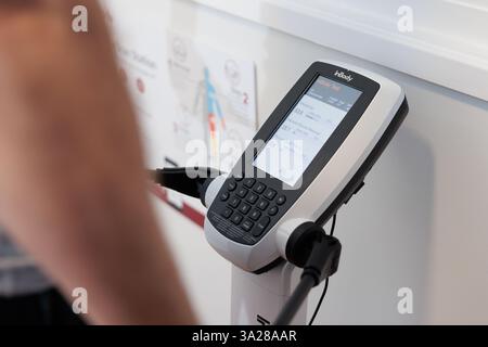 A person is standing in front of a machine that has a screen on it. The screen is displaying a number Stock Photo