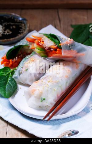 Summer or spring rolls with shrimp, vegetables and spinach, served with soy sauce and sesame. Traditional Vietnamese food. Rustic style, selective foc Stock Photo