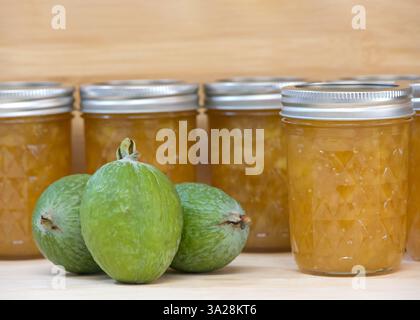 Close up on a jars of fresh homemade jam with fresh ripe Feijoa sellowiana also known as Acca sellowiana Burret or Pineapple Guava. light wood table w Stock Photo