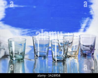 Various glasses on silver foil, blue coloured surface behind, studio shot Stock Photo