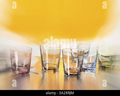 Various glasses on silver foil, yellow coloured area behind, zoom effect, studio shot Stock Photo
