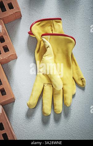 Set of orange construction bricks leather safety gloves on concrete surface building concept Stock Photo