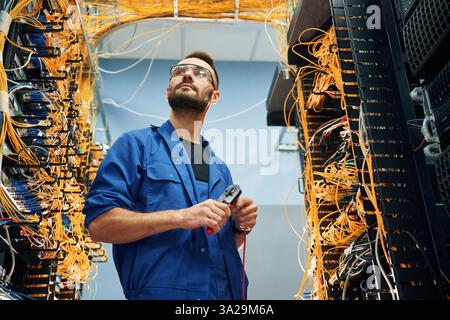 Handsome young man is working with internet equipment and wires in server room. Stock Photo