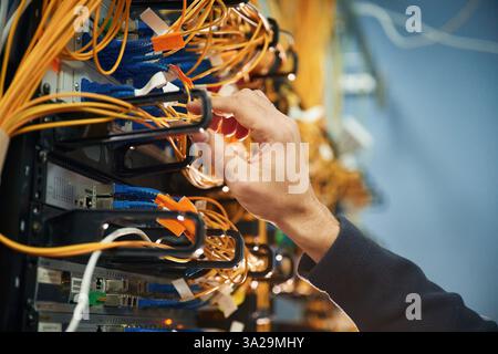 Young man is working with internet equipment and wires in server room. Stock Photo