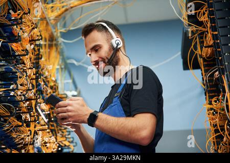 Young man is working with internet equipment and wires in server room. Stock Photo