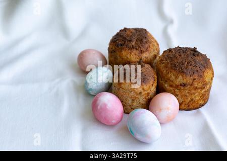 three whole wheat Easter cakes and pastel color Easter eggs on a white tablecloth Stock Photo