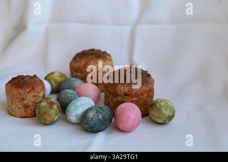 three Easter cakes and colorful eggs on a white tablecloth Stock Photo