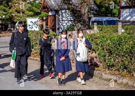 Japanese school children in uniform walking through a park in Kyoto, Japan. Stock Photo